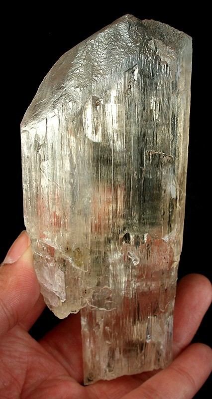 A large translucent spodumene crystal held in a hand